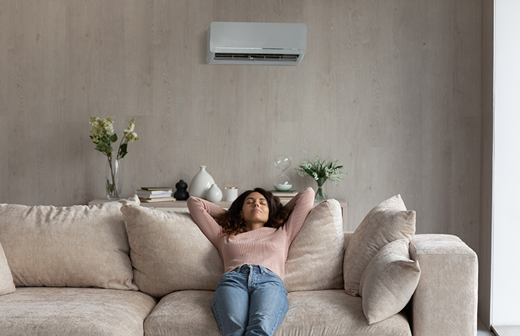 Picture of a woman relaxing in her home underneath an air conditioning unit