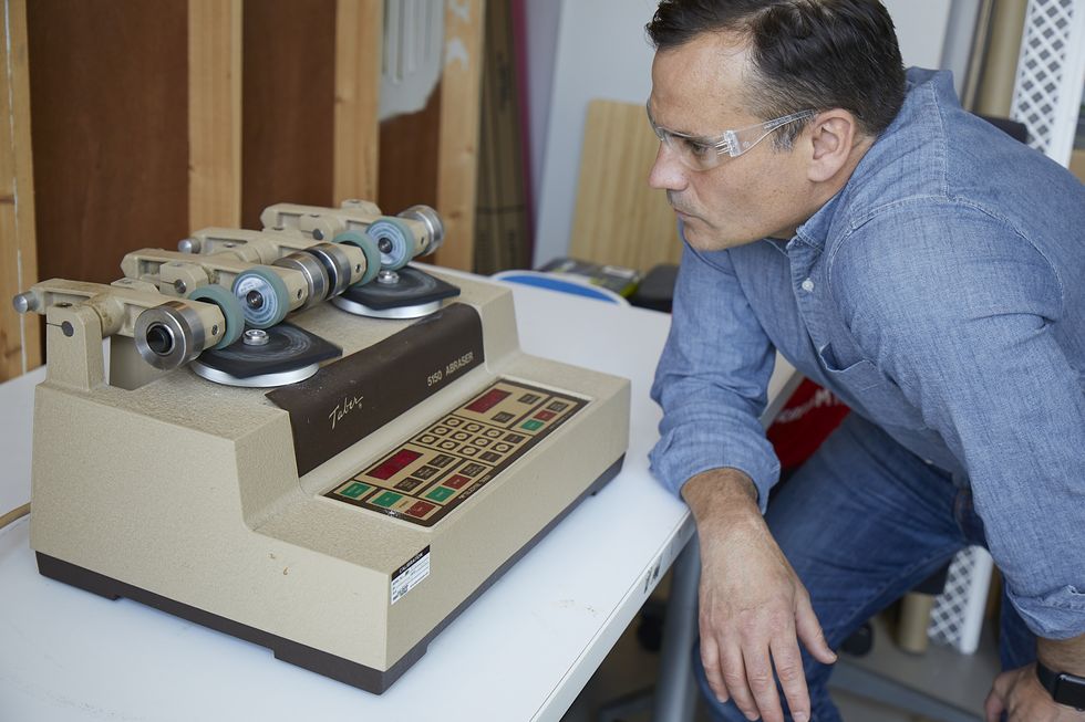 an expert at the good housekeeping institute uses an abrasion machine to test flooring's scratch resistance