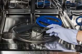 Person cleaning a dishwasher drain