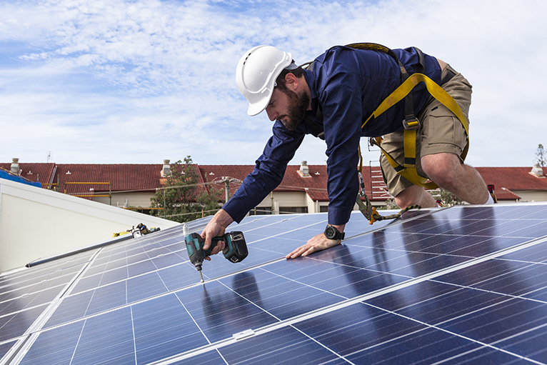 Solar panel installer working on roof