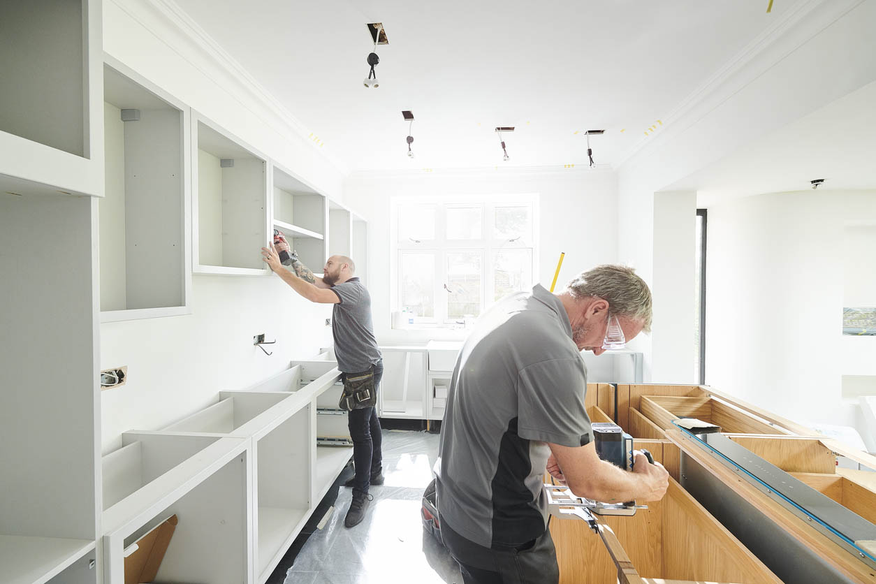 Two workers remodel a room. 